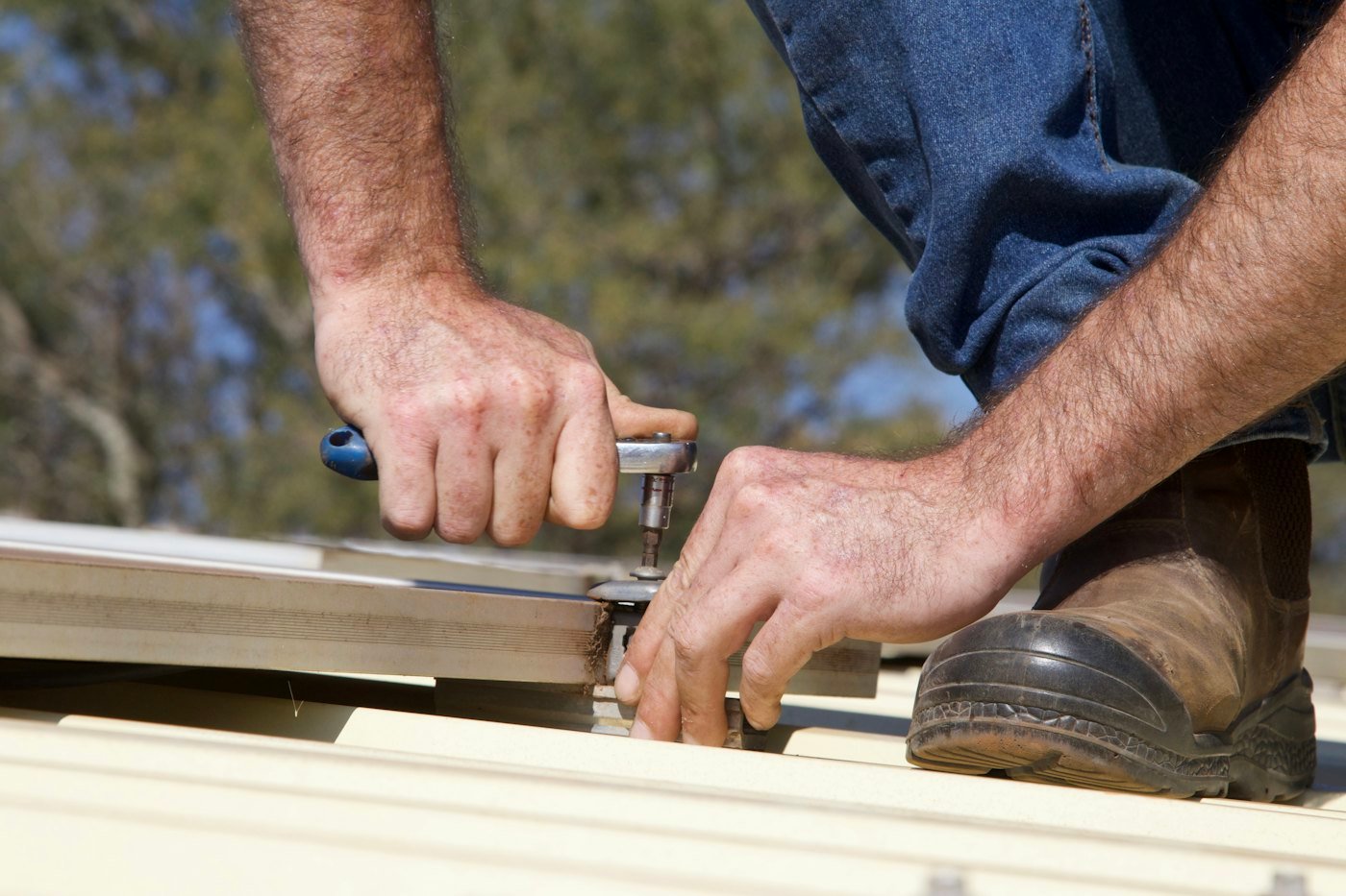 Hands fastening a metal roof panel